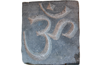 Le signe Om gravé en creux sur une plaque de pierre grise.