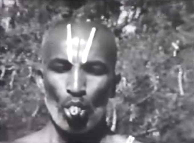 Portrait en noir et blanc d’un yogi, le front marqué de trois traits clairs, la langue roulée en tube entre les lèvres.