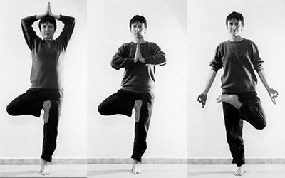 Vrikshāsana en trois temps : en équilibre sur une jambe, le pied opposé posé contre la jambe d’appui, les mains d’abord au-dessus de la tête, puis jointes devant la poitrine, puis posées sur les genoux.